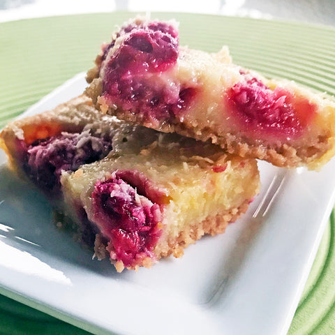 Luscious squares with a cookie crust and toasty coconut nestling bright, tart raspberries